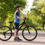 Kind steht neben einem 24 Zoll Fahrrad und erreicht mit beiden Fuessen den Boden
